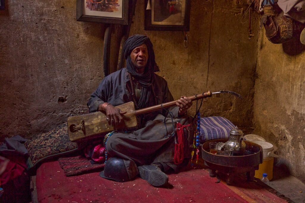 pexels-photo-16188297 A Moroccan musician playing a traditional instrument inside a Marrakesh home.