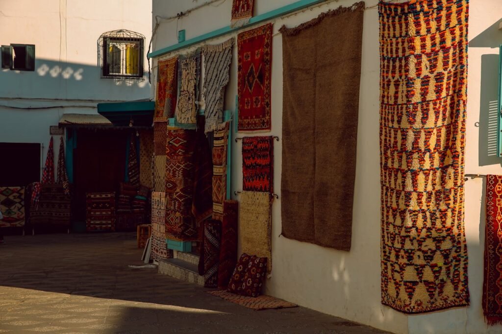 Colorful textiles and lanterns in the bustling souks of Marrakech Colorful handwoven Moroccan rugs on display in a vibrant Asilah market.