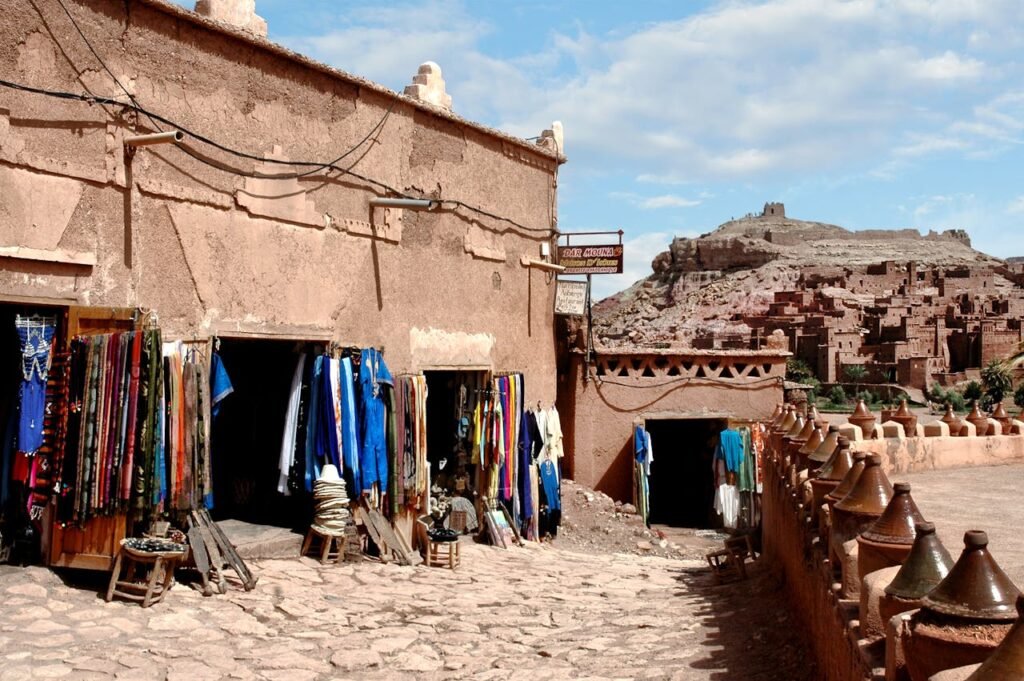 pexels-photo-30447654 Colorful market stalls in Ouarzazate, Morocco with historic kasbah backdrop.