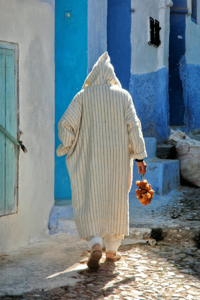 old man with jalaba walking with a moroccan food in his hand